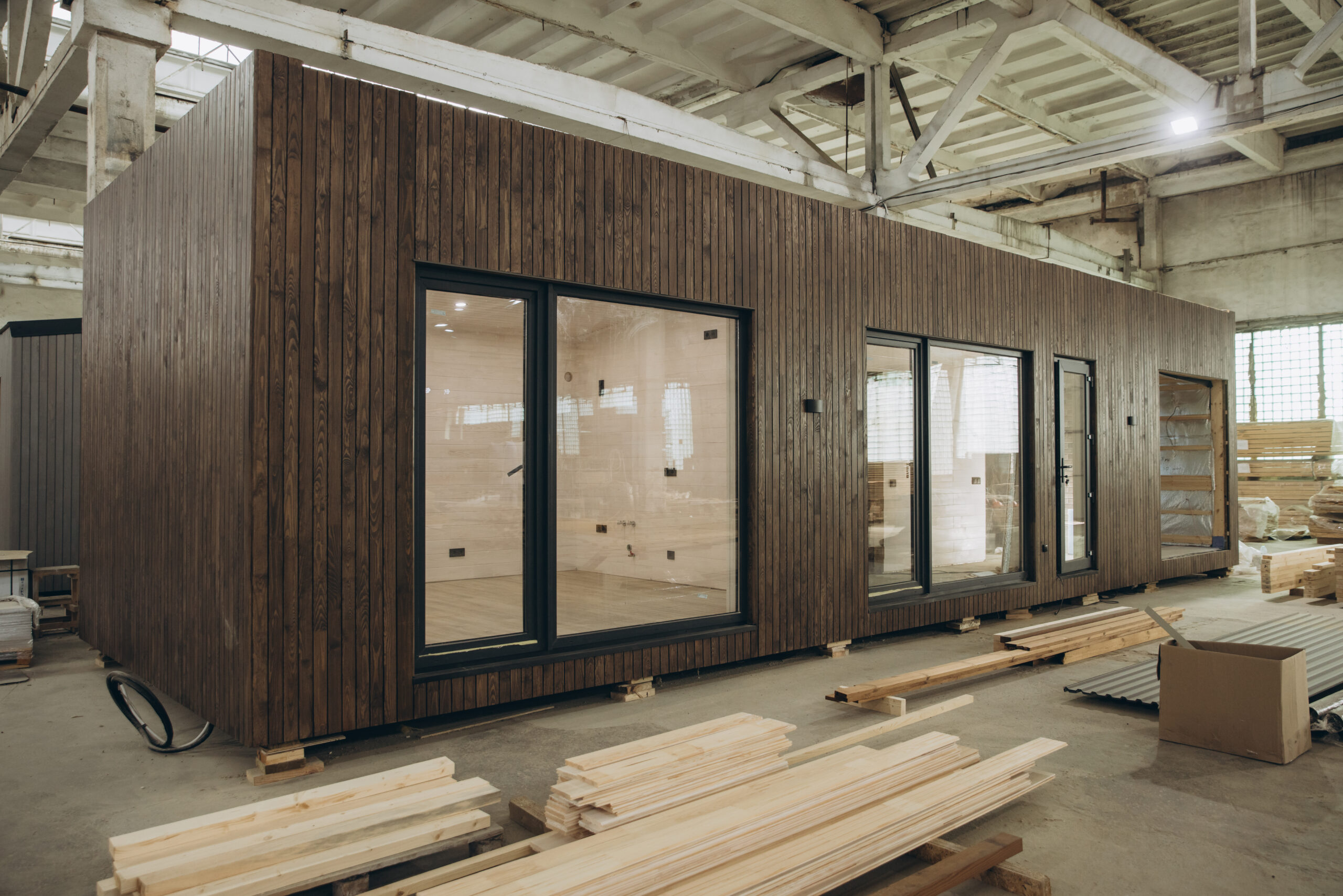 Modern prefabricated tiny house being built inside a spacious factory, showcasing the efficiency of modular construction