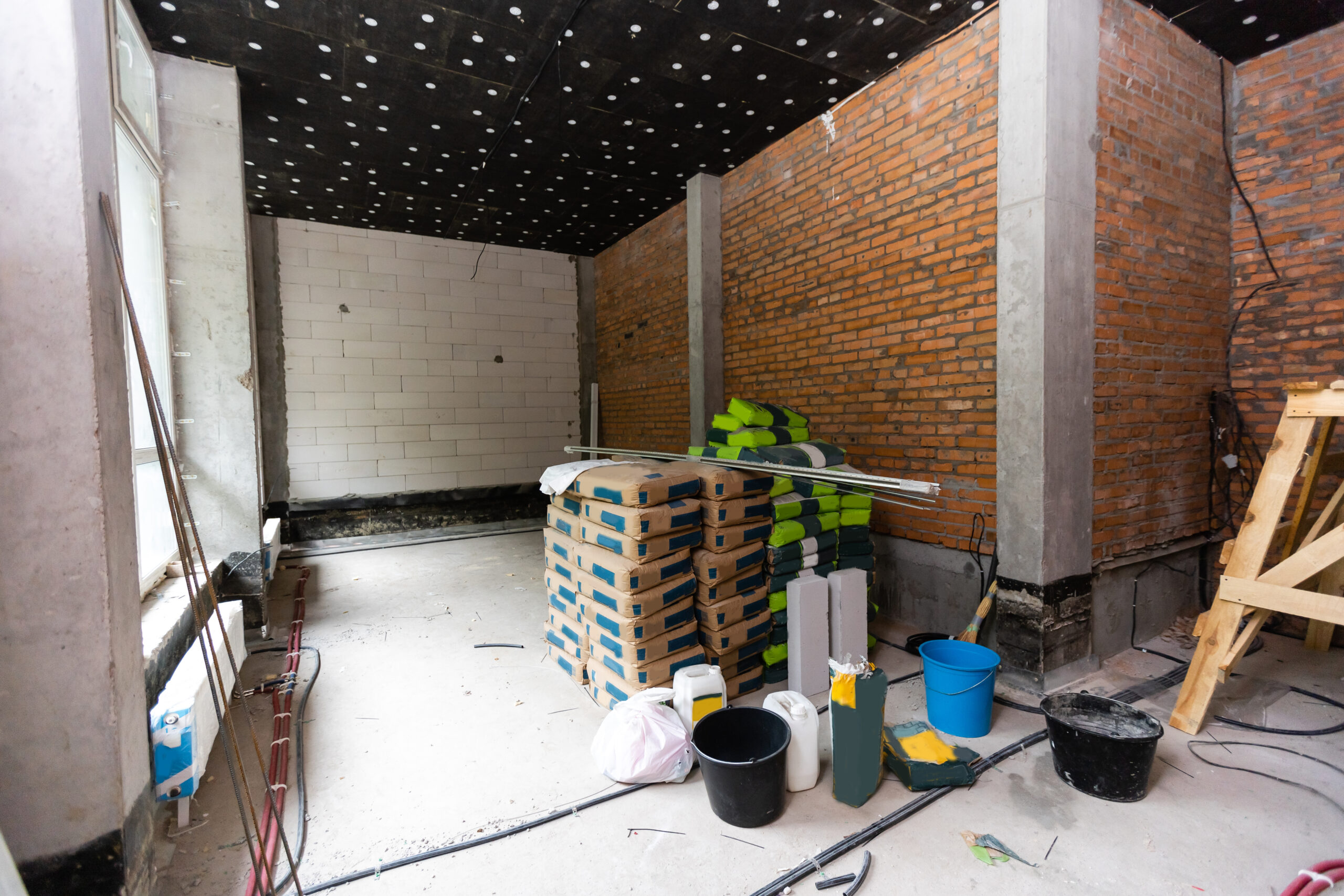 Newly renovated generic empty office space with leftover materials and ladder in foreground.